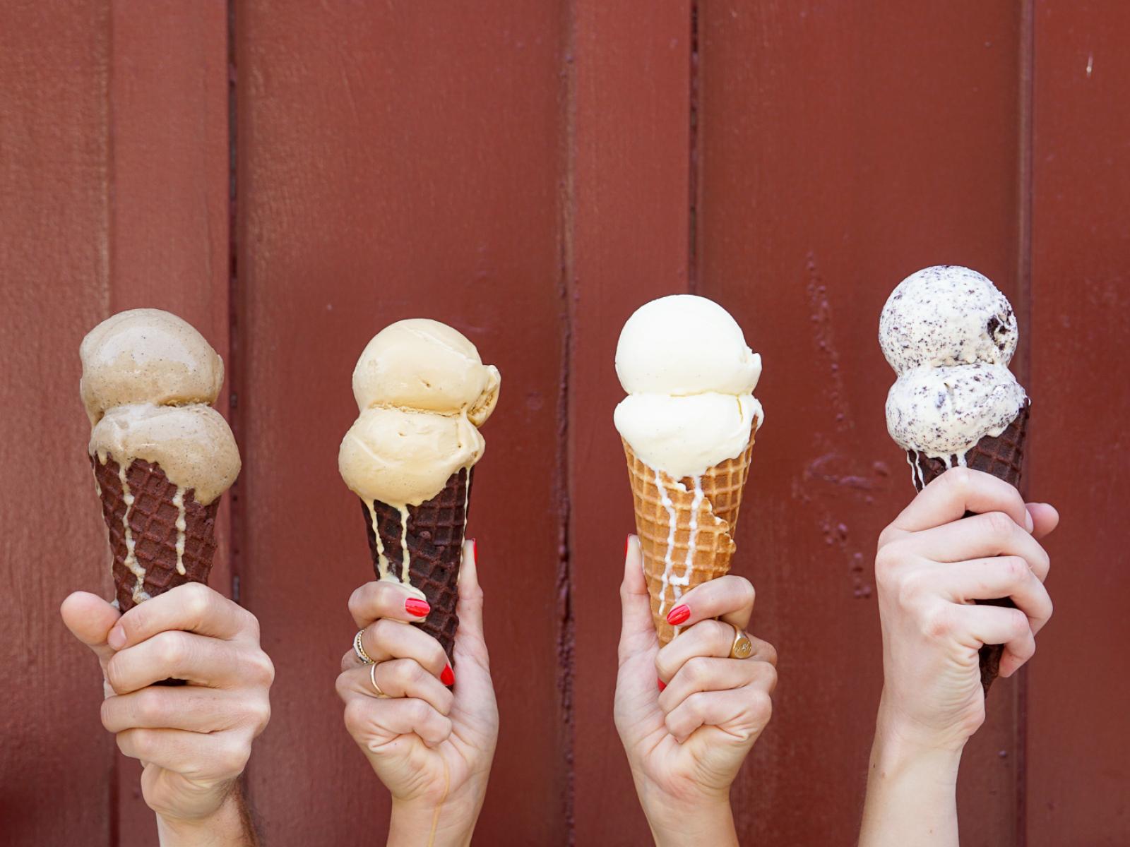 Hands holding a variety of ice cream cones from Sweet Rose Creamery